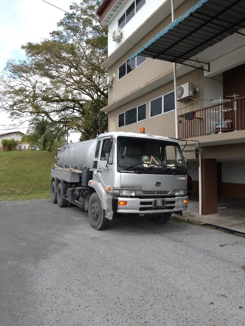 Desludging tanker parked beside a building on a service call